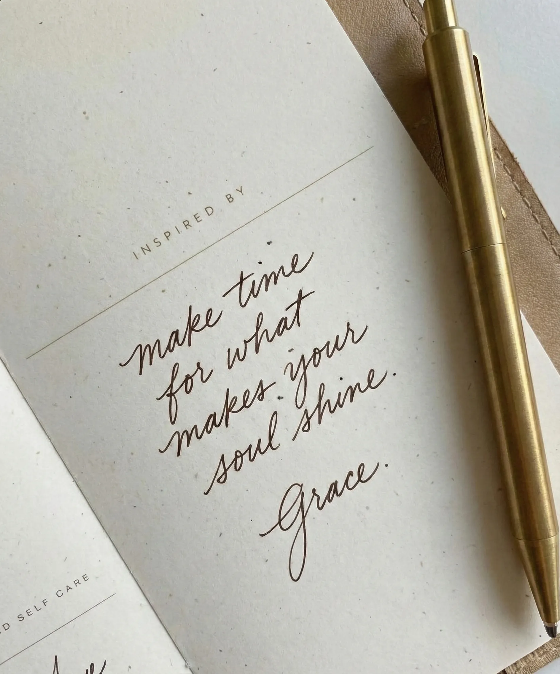 Close-up of a handwritten quote on textured paper beside a gold pen, with the name “Grace” signed at the bottom.